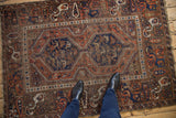 Vintage Kamseh rug with visible wear across knot heads, prominent double medallion, terracotta, navy.