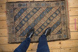 Worn blue, beige, and blush diamond panels in a lattice pattern on vintage Belouch rug.