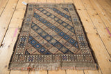 Worn fringe, geometric border, and diamond panels on vintage Belouch rug.