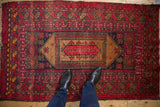 Cherry red, navy, brown Afghan rug with lozenge medallion and ram's horn borders.
