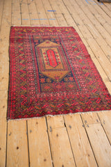 Vintage Afghan rug with cherry red field, coffee brown medallion, and navy blue borders.