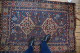 The covered field of a vintage Kamseh rug with a sapphire blue ground and animal motifs, viewed for scale.