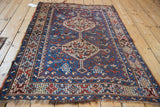Angled view of a vintage Kamseh rug highlighting its double medallions and geometric animal motifs.