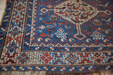 Even wear across the knot heads and geometric borders of a vintage Kamseh rug corner.