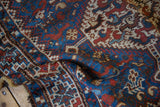 Time-softened low pile texture of a vintage Kamseh rug in sapphire blue and madder red.