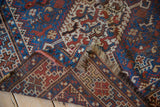 The hand-knotted back, low wool pile, and fringe of a vintage Persian Kamseh rug corner.
