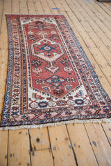 Hamadan runner's brick red field, navy geometric arrowed finials, and blush starburst border.
