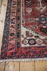 Close-up of vintage Hamadan rug border in navy blue, pale blush, and brick red Herati pattern, with worn fringe.