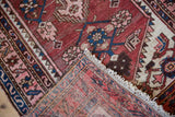 Vintage Hamadan rug showing hand-knotted weave, brick red pile, and white fringe.