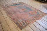 Worn left edge of antique Oushak rug, revealing exposed foundation, fringe, and faded border motifs.