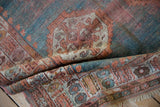 Antique Angora Oushak rug's folded border, revealing worn turquoise and peach motifs and tattered fringe.