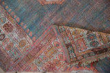 Angora Oushak rug fold revealing turquoise, pink pile, pomegranate border, exposed foundation, tattered fringe.