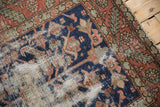 Karaja rug's worn navy field, serrated leaves, terracotta border, and visible foundation.