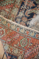 Detail of a vintage Karaja rug's worn pile, showing terracotta, navy, and foundation.