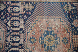 Antique Shirvan rug detail: Kufic border and geometric field motifs in time-softened navy, terracotta, and sand.