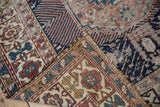 Worn navy, terracotta, and gold geometric patterns on a folded antique Shirvan rug edge.