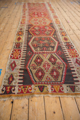 Geometric charcoal, red, and pale border with hexagonal medallion on a Turkish Kilim runner.