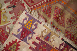 Folded vintage Turkish Kilim runner, highlighting flatweave, fringe, and front-to-reverse color contrast.
