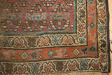 Corner of antique Kurdish Hamadan rug, showing aubergine field, patterned borders, tattered edge.