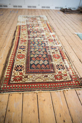 Vintage Caucasian runner detail: dark blue field with boteh motifs, pawn border, and exposed foundation.