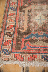 Vintage Hamadan rug corner with geometric red, blue border, foundation wear, and tattered fringe.