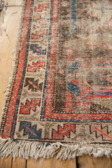 Vintage Hamadan rug corner with tattered fringe, visible foundation, and red, blue, beige border.
