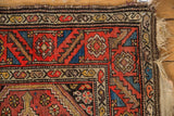 Tattered beige fringe and side border loss on a geometric red, blue, brown Kurdish Hamadan rug.