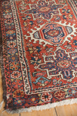 Vintage Persian Karaja rug's tattered side border and brick red field with floral pinwheel motifs.