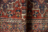 Vintage Karaja rug folded, revealing hand-knotted pile with red, blue, ivory traditional patterns.