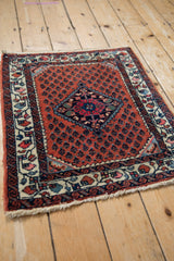 Angled view of a vintage Persian Engelas rug, showing its brick red boteh field and central diamond medallion.
