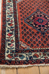 Corner view of a vintage Engelas rug showing its ivory blossom border and red boteh field.