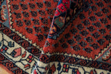 The dense wool pile of a folded vintage Engelas rug with brick red boteh and blossom motifs.