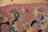 Dusty rose Nichols Art Deco rug's tattered edge, black branches, and colorful lotus blossoms.