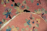 Detail of the vintage Art Deco rug's dusty rose floral pile and hand-knotted woven foundation.