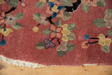 Tattered edge of Art Deco rug, showing dusty rose, black tendrils, and floral motifs.