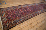 Vintage Malayer runner shown at a long angle, highlighting its meandering vine border and navy field.