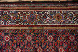 Tattered edge of a vintage Malayer runner showing the samovar turtle design border and worn pile.