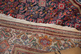 A vintage Malayer rug's tattered edge, showing the contrast between the navy field and sand border.