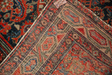 Hand-knotted Hamadan rug showing dense foundation, vivid red patterns, and edge wear.