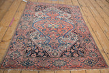 Coral field of this vintage Farahan Sarouk rug, with interconnected blossoms and navy blue vinery.