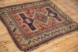 Worn fringed edge and geometric borders of a hand-knotted antique Kazak rug.