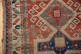 Antique Caucasian Kazak rug corner, geometric Avar cartouche, checkered motif, cherry red, navy, ivory.