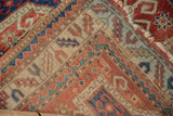 Exposed knot heads, tattered edge, and hand-knotted foundation of an antique Kazak rug.