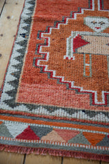 Distressed Kurd runner corner with primitive zig-zag border and short rust fringe.