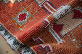 Distressed Kurd runner's rolled edge, textured pile, and zigzag border in rust, ivory, oxidized silver.