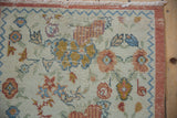 Distressed Oushak rug: rust main border, blue chevron pattern, and worn ivory floral field.