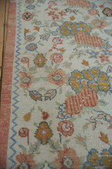 Distressed Oushak runner with textured floral bouquets and light blue chevron border.