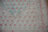 Distressed vintage Oushak rug detail with faded raspberry botehs on ivory, mint green accents.