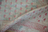 Rolled distressed Oushak rug showing pale raspberry, mint, ivory staggered patterns and even wear.