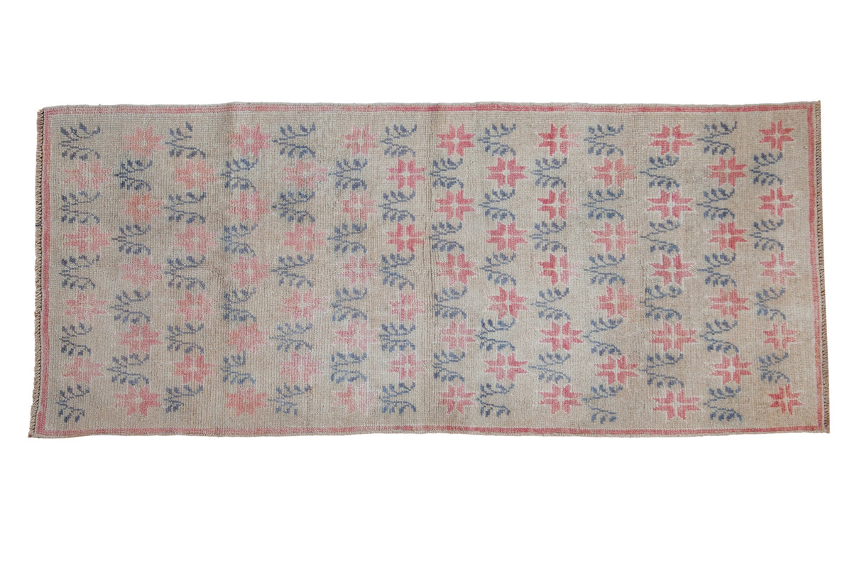 Distressed vintage Oushak runner with raspberry starbursts and teal vines on a platinum field.
